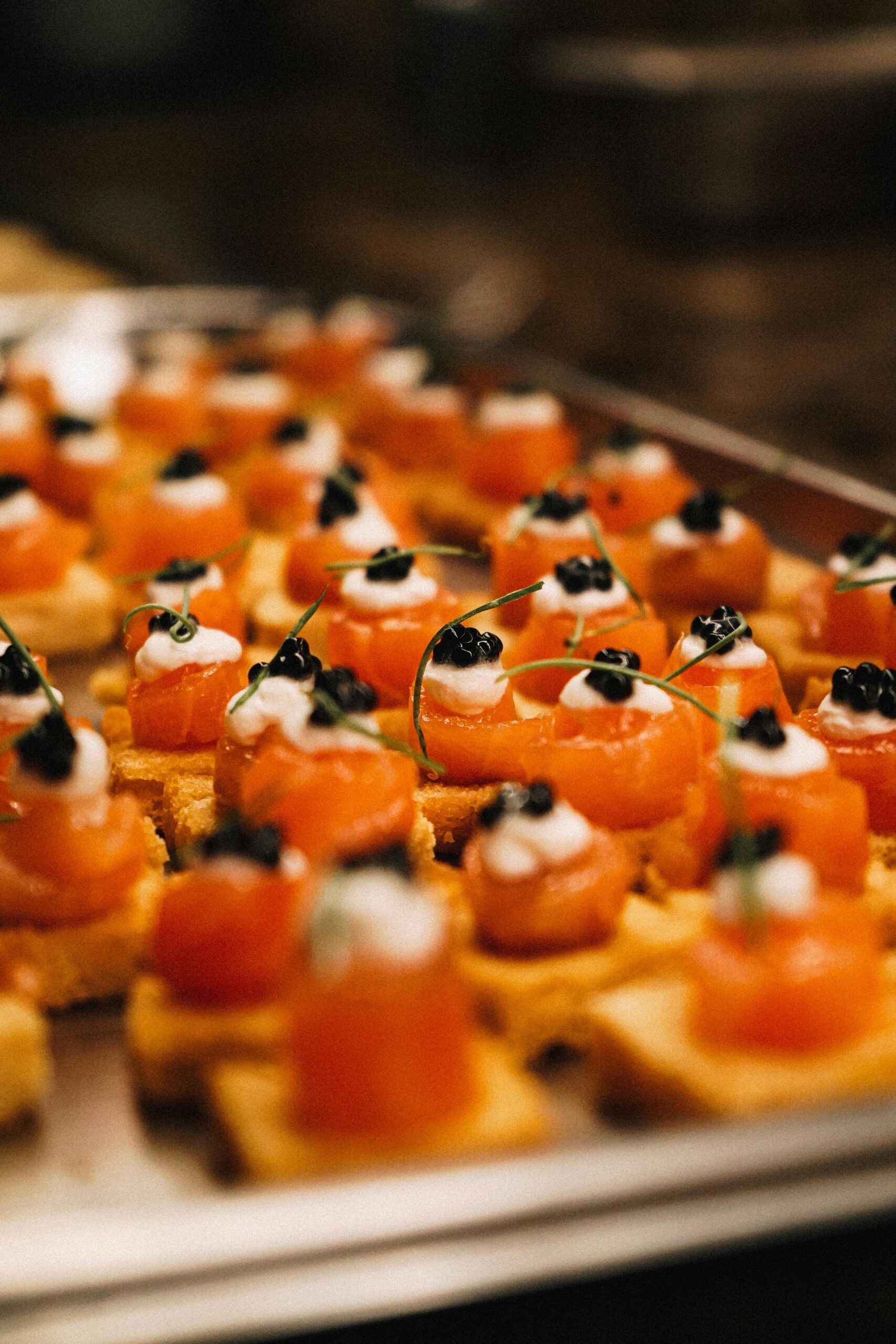 Close-up of gourmet canapés topped with salmon and caviar, perfect for luxury events.